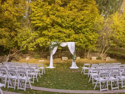 chairs set on either side of an aisle facing an arch draped in white