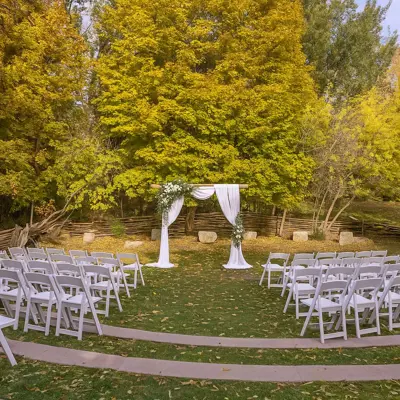 chairs set on either side of an aisle facing an arch draped in white