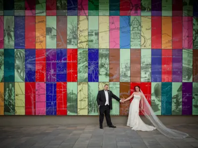 wedding couple posing in front of colourful glass wall