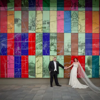 wedding couple posing in front of colourful glass wall