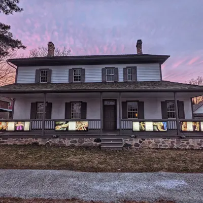 front view of exterior of Schneider Haus at dusk showing lit up light boxes of pictures