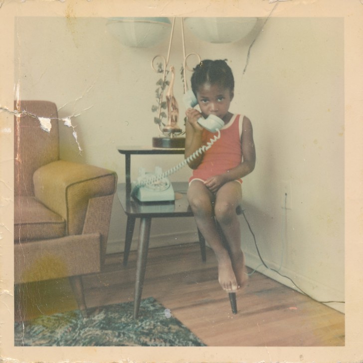 little girl sitting on table holding phone