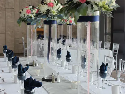 table set for wedding dinner featuring tall vases topped with flowers