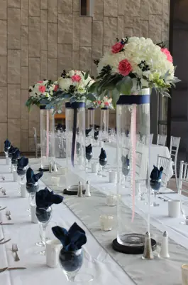 table set for wedding dinner featuring tall vases topped with flowers