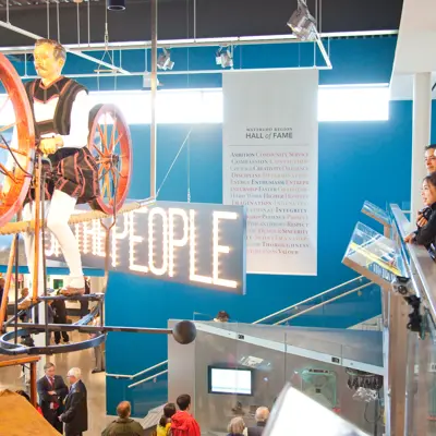 people standing at mezzanine railing looking at exhibit piece