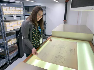 woman looking at large paper document on light table