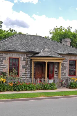 stone cottage surrounded by a picket fence and yellow and red flowers