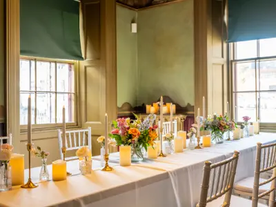 long table set for dinner with white tablecloth, flowers and candles