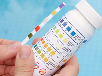 person holding ph strip next to bottle of tests