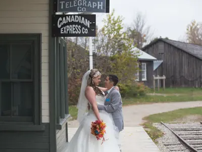 two women in wedding wear kissing in front of the train station