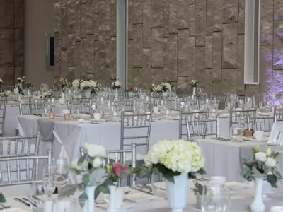 groups of tables covered in white table cloths set against stone wall